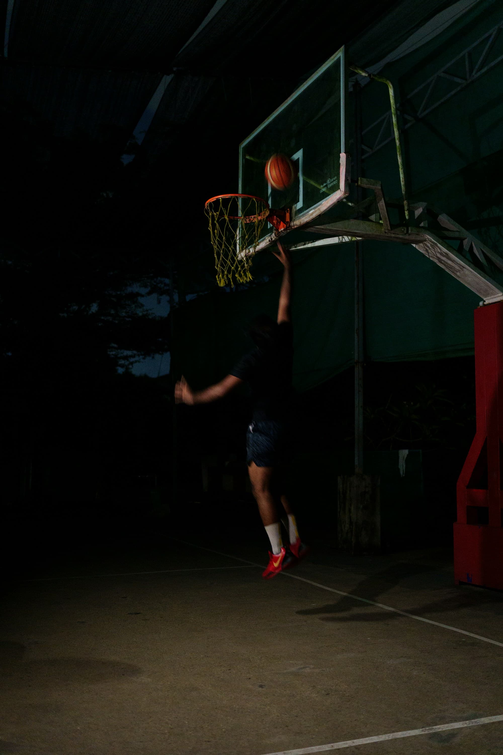 Basketball player rising toward the hoop under the court lights